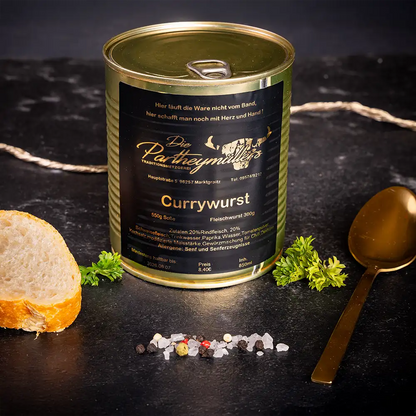 Goldene Konservendose der Metzgerei Partheymüller mit Currywurst, edel präsentiert auf dunklem Untergrund mit frischen Kräutern, Pfefferkörnern, Meersalz und einer Baguettescheibe