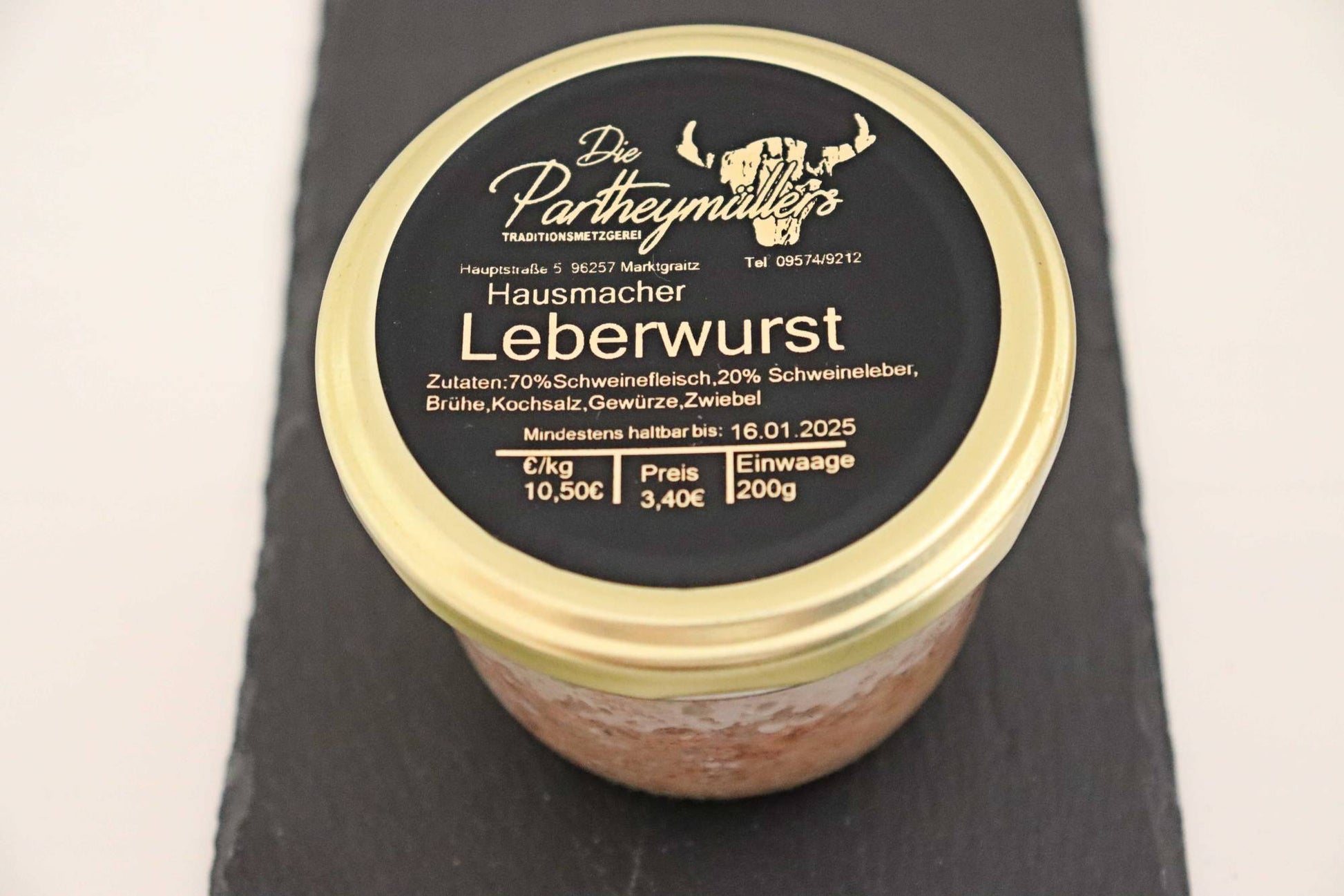 Ein Glas mit Leberwurst von der Firma Partheymüller, mit schwarzem Etikett auf goldenem Deckel.