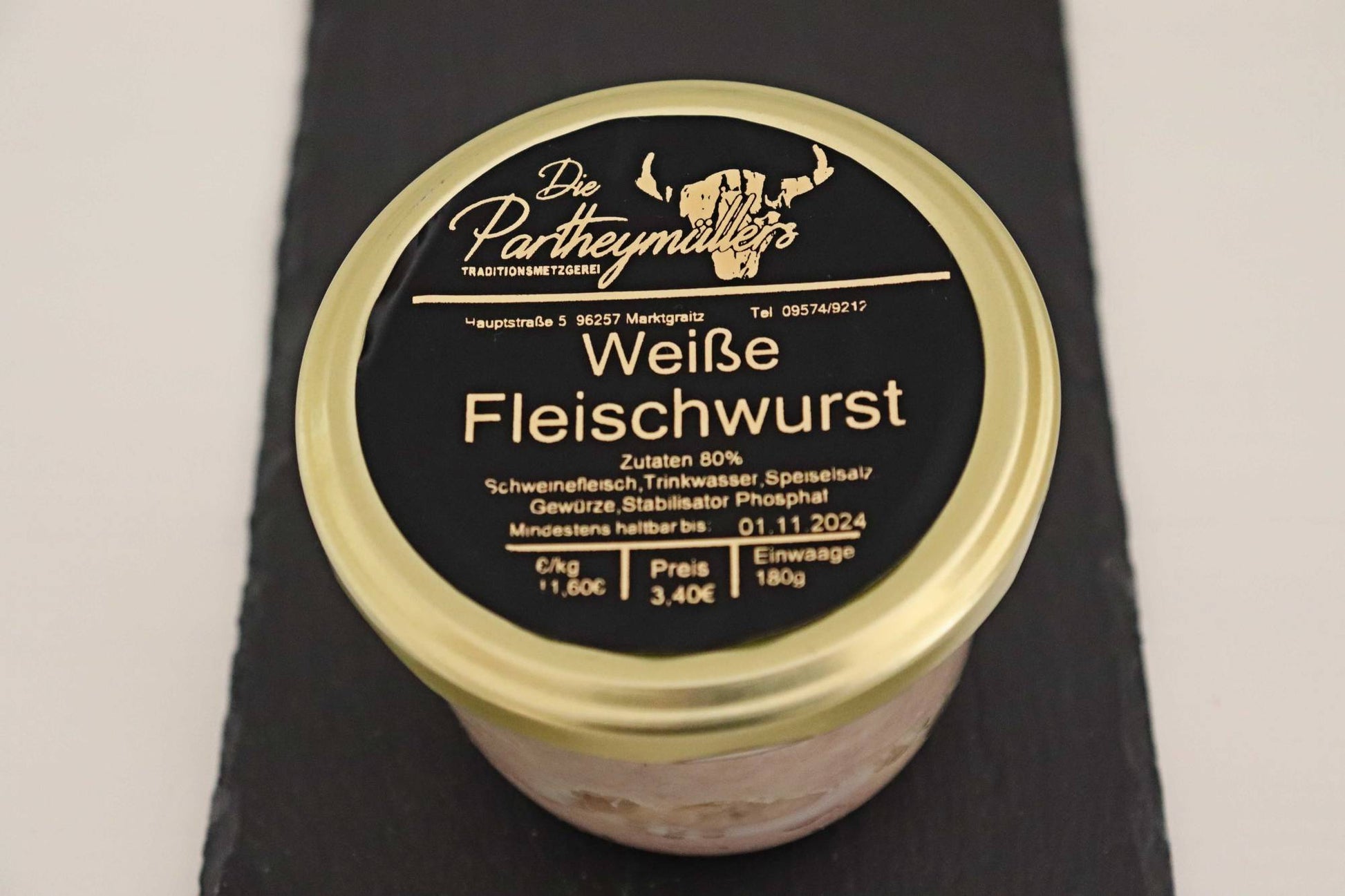 Ein Glas mit weisser Fleischwurst von der Firma Partheymüller, mit schwarzem Etikett auf goldenem Deckel.