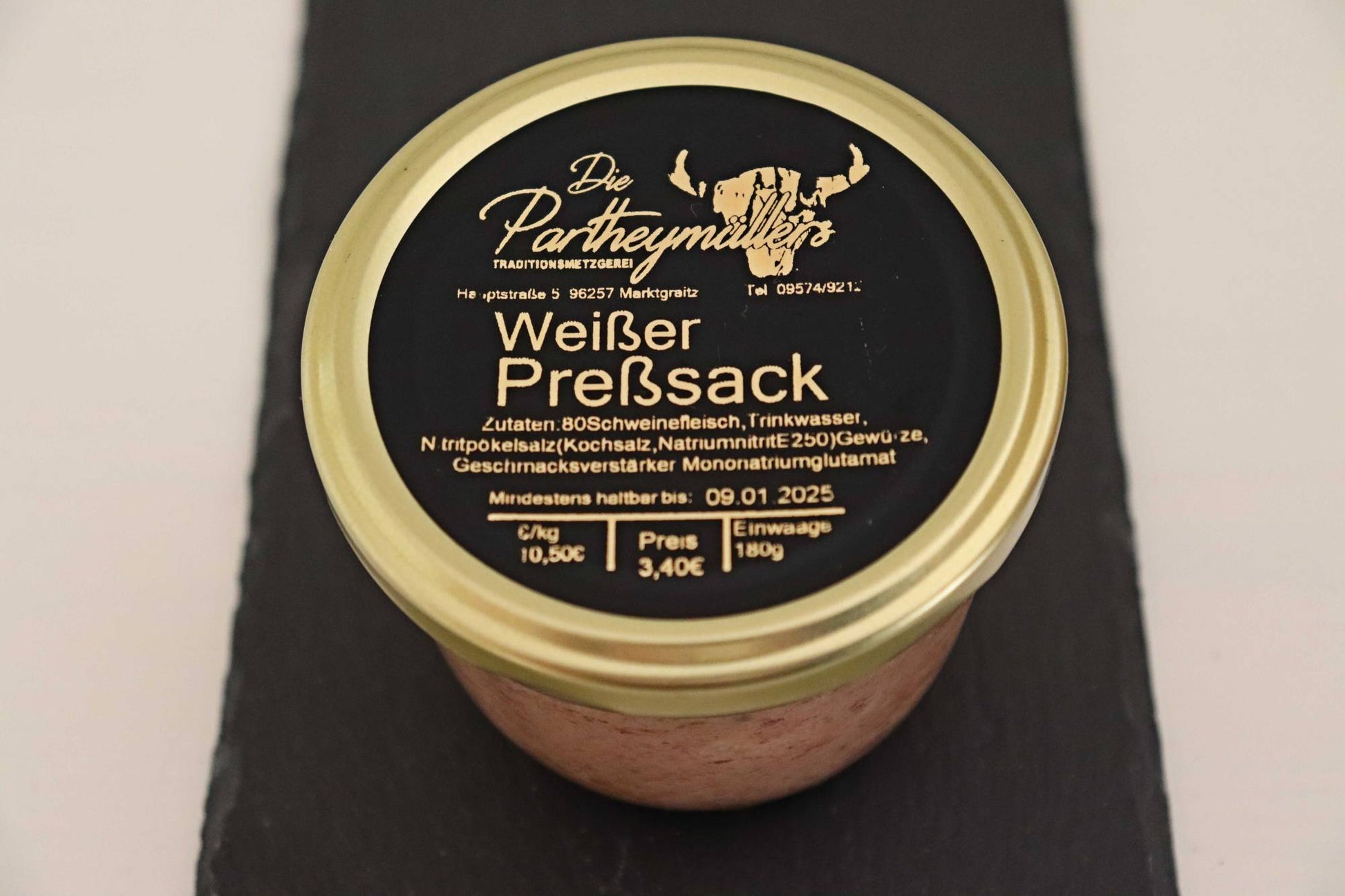 Ein Glas mit weissem Pressack von der Firma Partheymüller, mit schwarzem Etikett auf goldenem Deckel.
